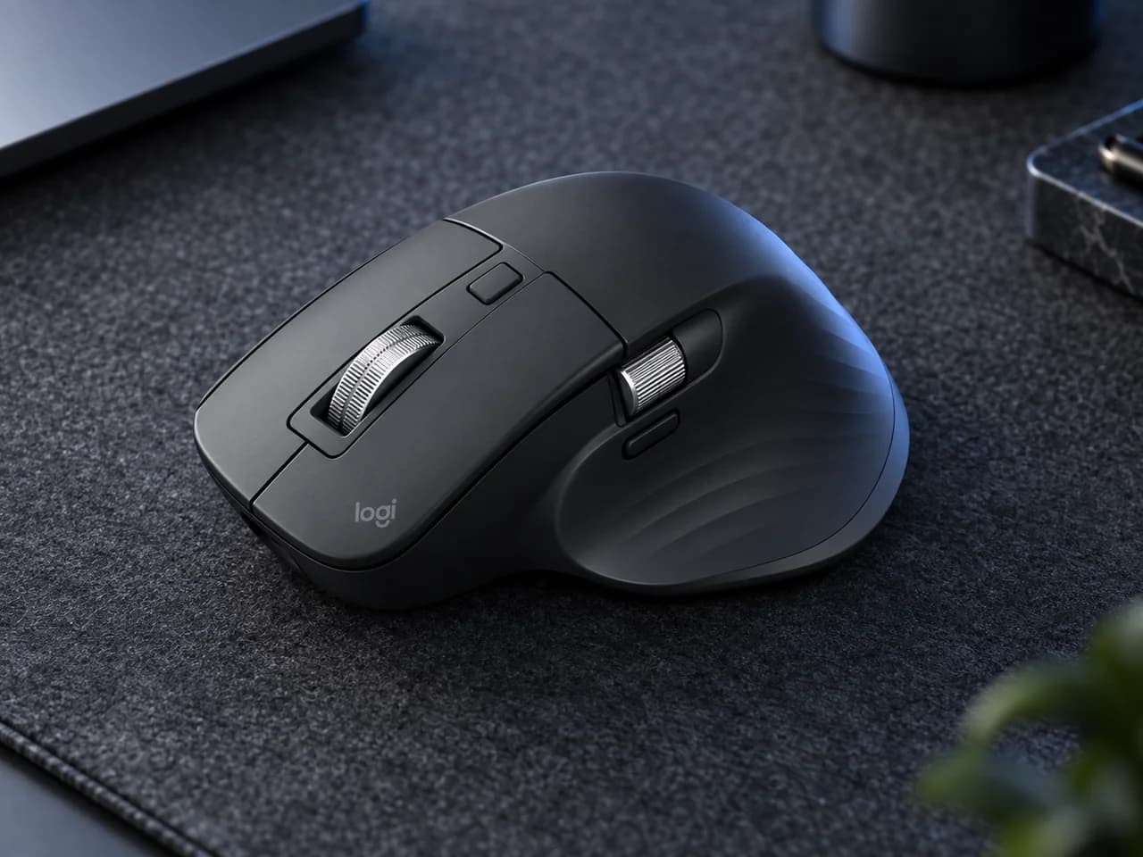 어두운 펠트 데스크 매트 위에 사선으로 놓인 블랙 Logitech MX Master 3S 무선 마우스