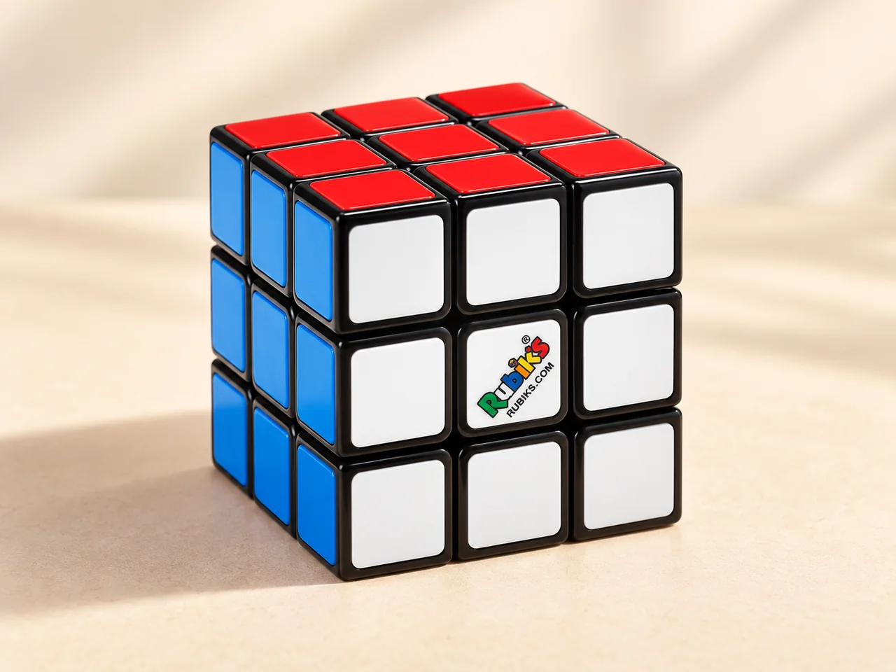 부드러운 크림색 배경 위에 놓인 완성된 루빅스 큐브 3×3