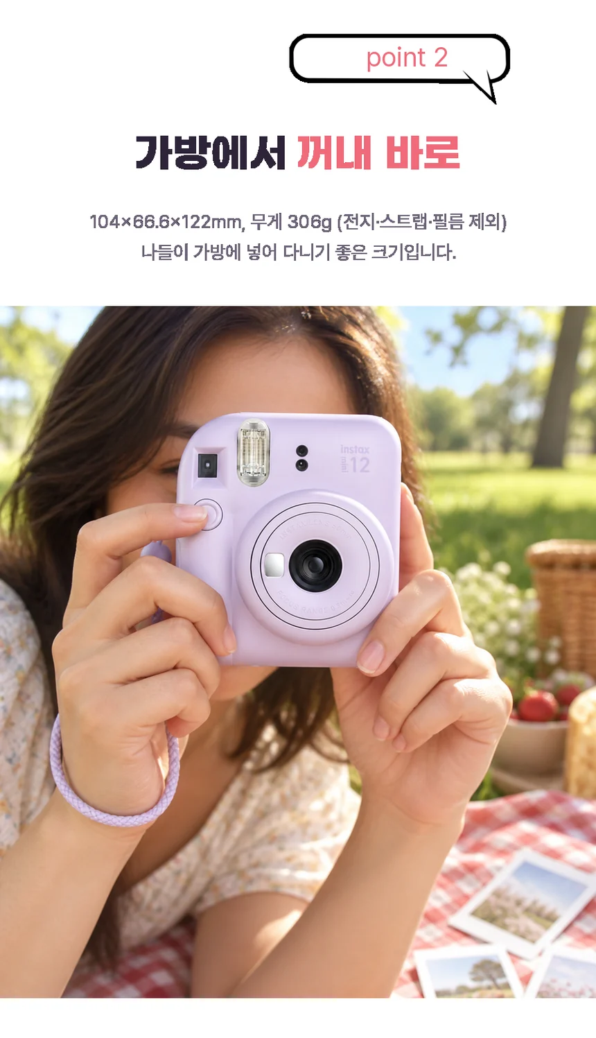 햇살 좋은 공원 피크닉에서 두 손으로 instax mini 12를 들고 촬영하는 모습. 104×66.6×122mm, 무게 306g(전지·스트랩·필름 제외).